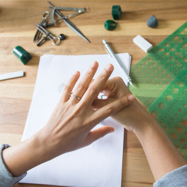 Drawing tools and hands creating design on white paper